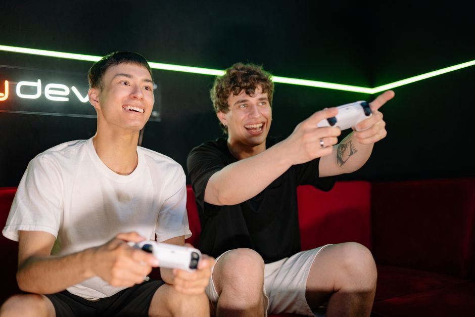 Two young men playing video games indoors, having fun and engaging with controllers.