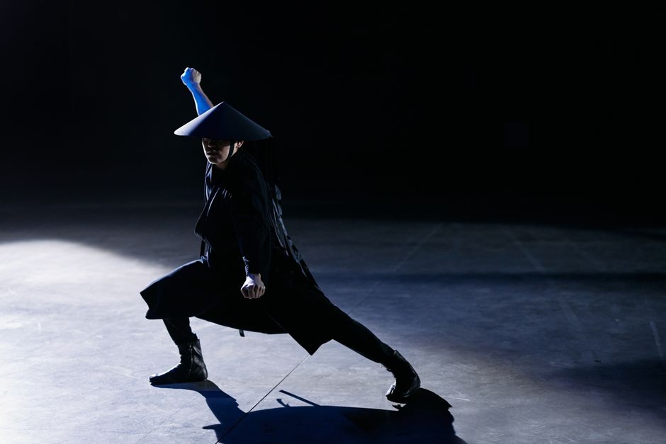 A skilled cosplayer strikes a dramatic pose as a game character in a dark studio setting.