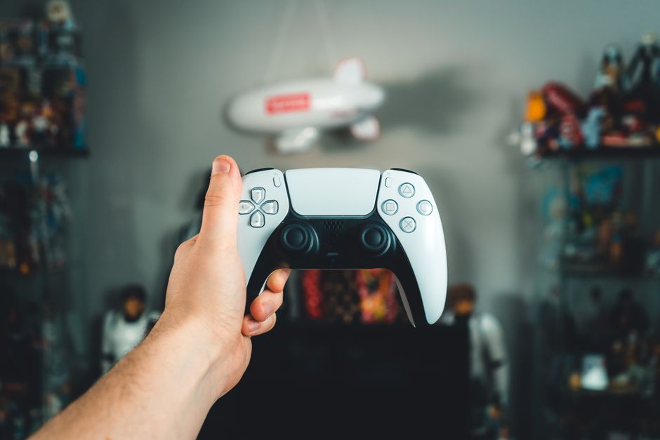 A close-up of a hand holding a sleek white gaming controller, showcasing modern design.