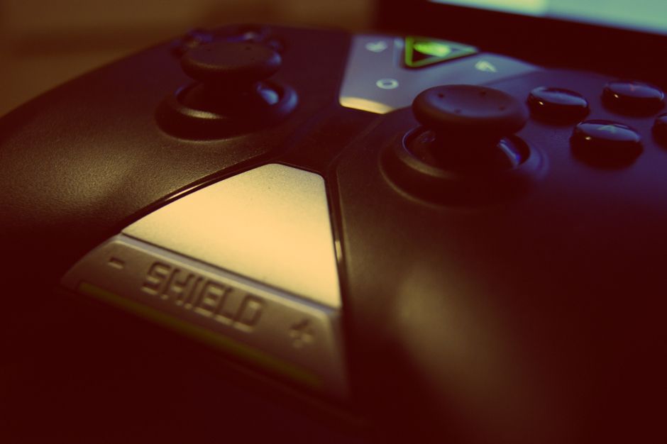 Close-up view of a modern gaming controller, highlighting joystick and buttons with a 'shield' design.