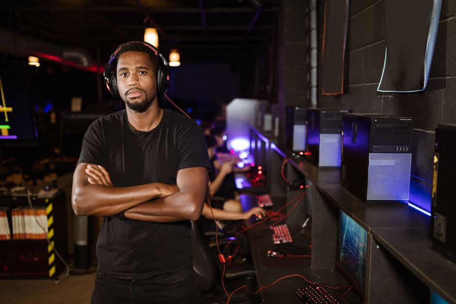 Young man standing confidently in a modern esports arena with computers.