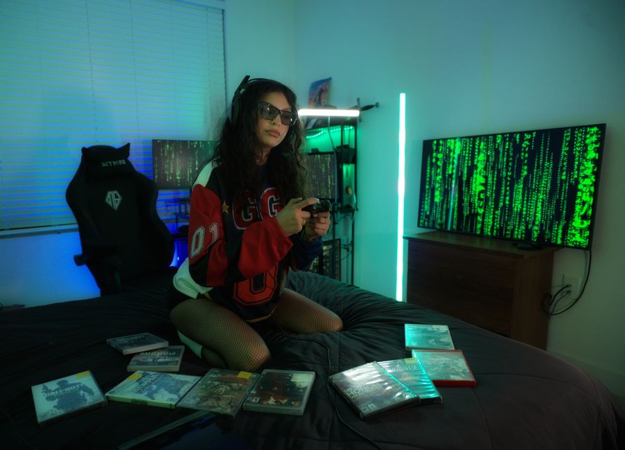 A young woman enjoying video games in a neon-lit room with a futuristic setup, surrounded by game cases.
